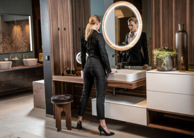 HOLTER_dunkles modernes Badezimmer mit huebscher Frau vor dem Spiegel
